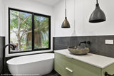 Modern bathroom with a freestanding bathtub, sink, and large window.