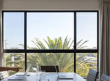 Modern office space with large windows showing palm trees outside.