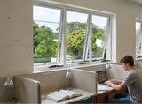 Person working on a laptop at a desk with a large window view of greenery