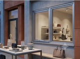 Store window display with handbags and decor items on a table.